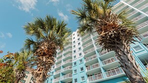 Un hotel de varios pisos con balcones y palmeras.