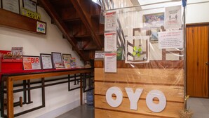 A reception desk with a wooden counter and the word "OYO" prominently displayed. There are various signs and notices on the wall, including a COVID-19 safety notice. - Roccksar Pension (Puerto Princesa)
