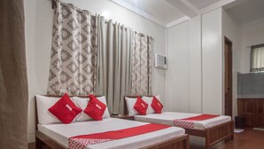A hotel room with two wooden beds, each with white bedding and red pillows. - Roccksar Pension (Puerto Princesa)
