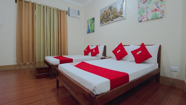 A hotel room with two beds, a wooden floor, a curtain, an air conditioner, and two wall art pieces. - Roccksar Pension (Puerto Princesa)