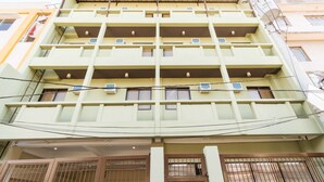 A multi-story building with balconies, air conditioning units, and a gated entrance. - RedDoorz Plus near Osmena Highway 2 - Quarantine Hotel (Manila)