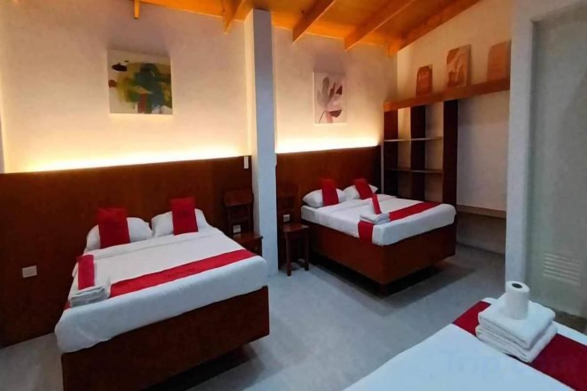 A hotel room with two beds, a small table, and a window.