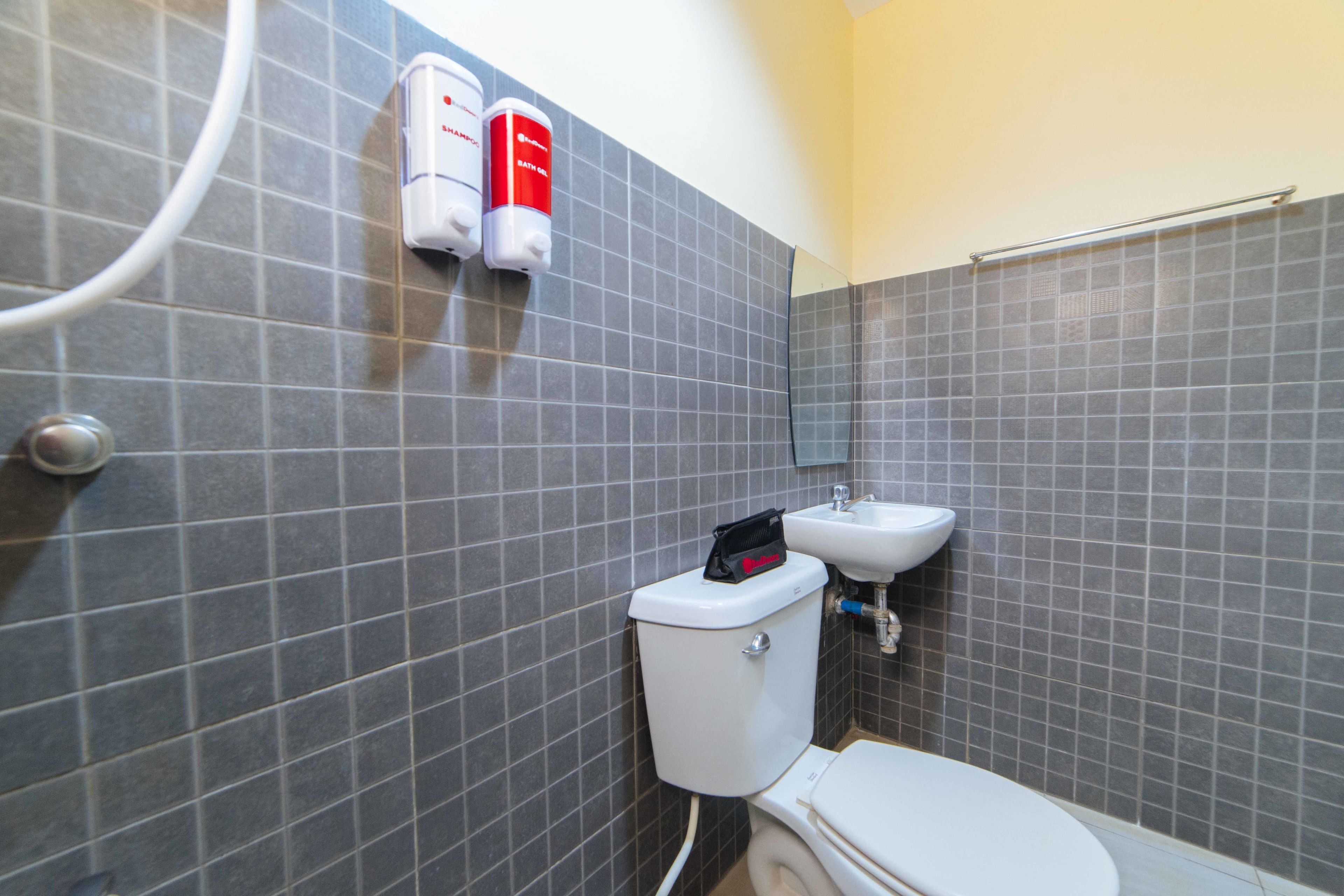 A bathroom with a toilet, a sink, and two soap dispensers mounted on the wall.