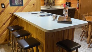 Una cocina rústica con una isla de madera, taburetes de bar y un cuadro enmarcado con osos.