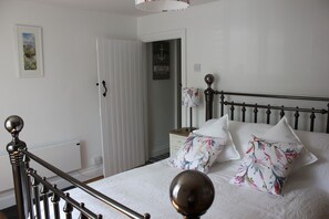 Une chambre à coucher avec un lit, une table de chevet, une lampe et une porte.