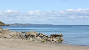 A coastal beach with rocky outcrops and calm sea.
