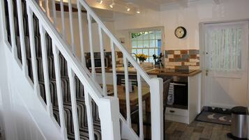 A kitchen with a wooden staircase, a clock, and a window with a view.