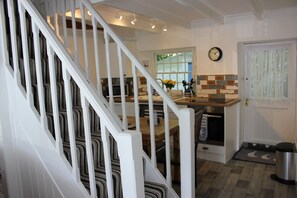 A kitchen with a wooden staircase, a clock, and a window with a view.