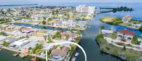 An aerial view of a coastal residential area with a marina, houses, and a large hotel.