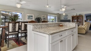 A spacious kitchen with a central island, white cabinetry, and a dining area with chairs. - Waterfront-canal/w/Gulf view-pets welcome-private dock for a fee. (Hudson)