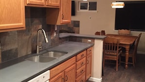 A kitchen with wooden cabinets, a dishwasher, a sink, and a dining area with a table and chairs. - Location! Historical District Downtown - Walk everywhere, new 4 Bedroom, 3 Bath (Bend)