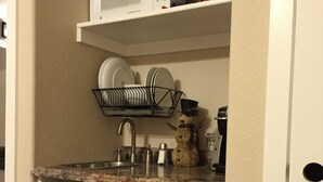 A kitchen with a microwave, dish rack, and a poster of a woman. - Location! Historical District Downtown - Walk everywhere, new 4 Bedroom, 3 Bath (Bend)
