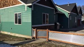 A green house with a wooden porch and a metal gate. - Location! Historical District Downtown - Walk everywhere, new 4 Bedroom, 3 Bath (Bend)