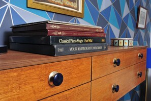 A stack of books on a wooden dresser with drawers and knobs. - The Beauty Rooms (Liverpool)
