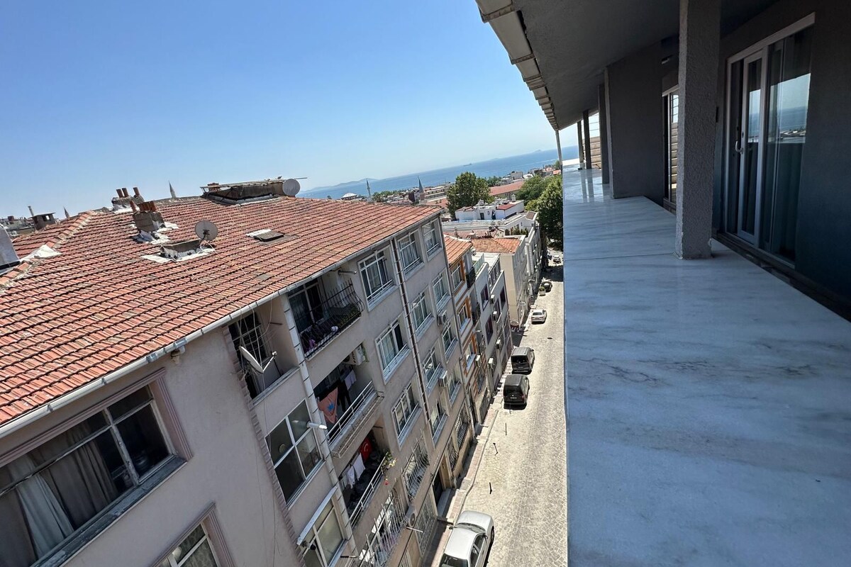 A balcony with a view of a cityscape and the sea.