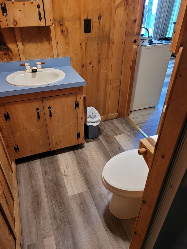 Une salle de bain en bois avec un lavabo, des placards et des toilettes.