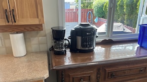 A kitchen with wooden cabinets, a coffee maker, and a Ninja blender on the counter. - Swimming pool, Family friendly home! (Penticton)