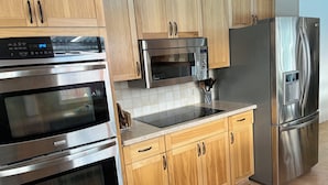 A kitchen with stainless steel appliances, wooden cabinets, and a tiled backsplash. - Swimming pool, Family friendly home! (Penticton)
