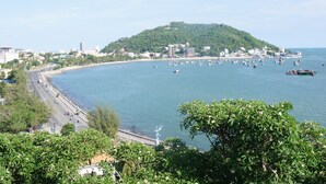 A coastal cityscape with a prominent hill, a beach, and numerous boats on the water. - RedDoorz Plus near Bai Truoc (Ho Chi Minh City)