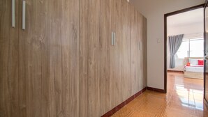 A hallway with a wooden panel wall and a tiled floor leading to a bedroom with a bed and curtains. - RedDoorz Plus near Bai Truoc (Ho Chi Minh City)