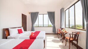 A hotel room with two beds, a wooden chair, a small table, and a view of the sea through large windows. - RedDoorz Plus near Bai Truoc (Ho Chi Minh City)