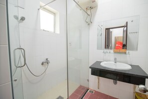 A bathroom with a glass-enclosed shower, a sink with a black countertop, and a mirror above the sink.
