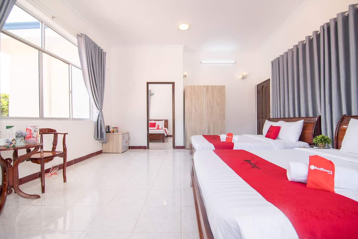 Habitación de hotel con dos camas, un escritorio y una silla.