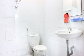 A small, clean bathroom with white tiles, a toilet, a sink, and a mirror.