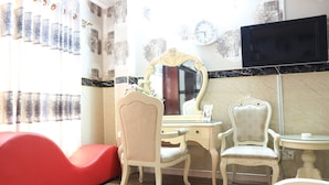 A room with a vanity, two chairs, a red sofa, a television, and patterned wallpaper. - RedDoorz @ Cong Hoa Street (Ho Chi Minh City)