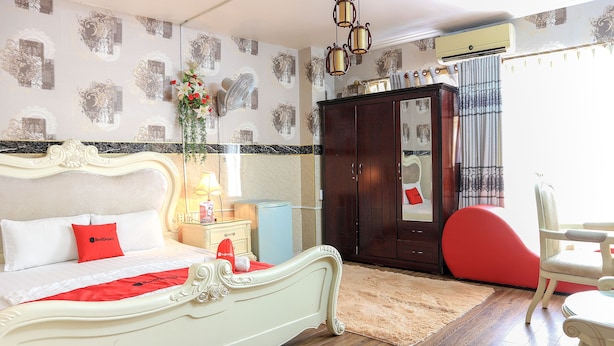 A bedroom with a white bed, a red pillow, a wooden wardrobe, and a red chair. - RedDoorz @ Cong Hoa Street (Ho Chi Minh City)
