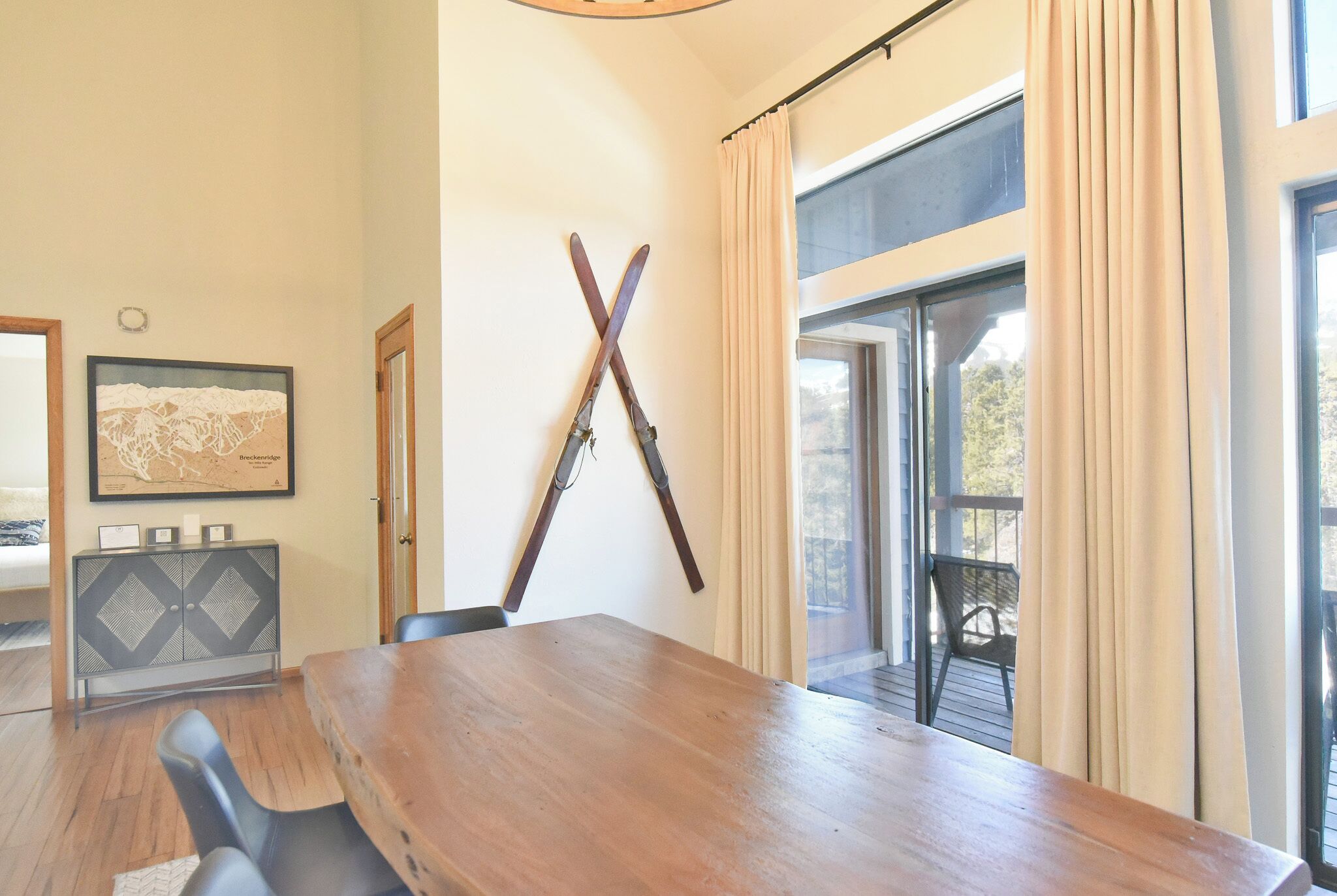 A dining area with a wooden table, black chairs, a black and gray cabinet, and a framed map on the wall.