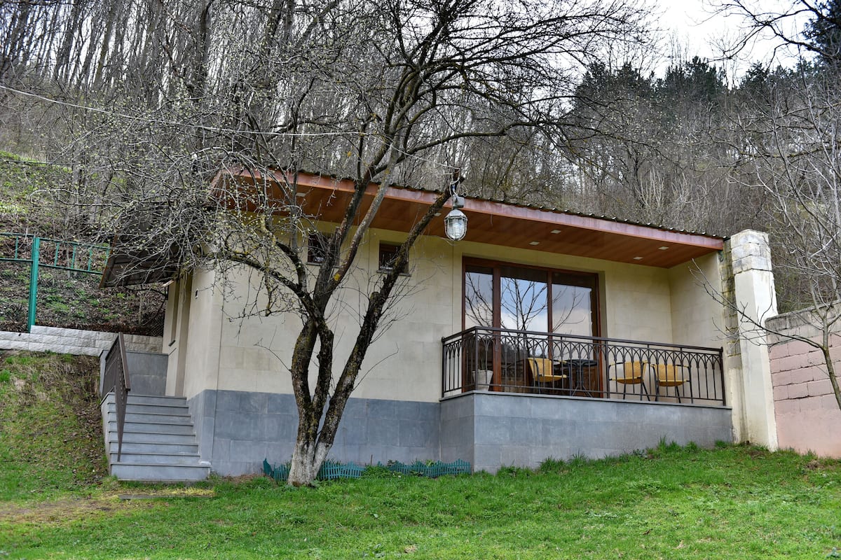 A two-story building with a balcony, a staircase, and a tree in front.