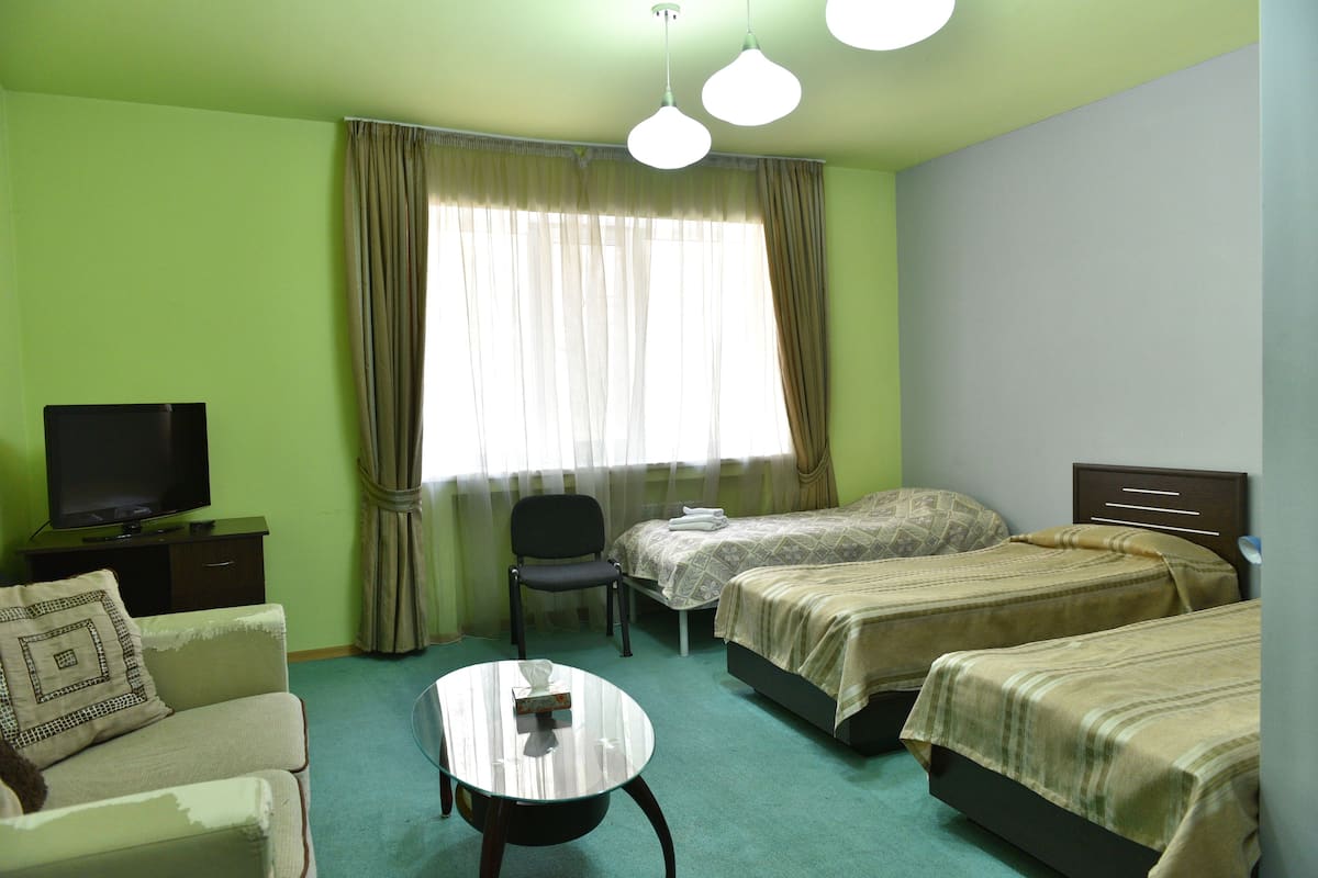 A hotel room with two beds, a TV, a chair, and a small table.