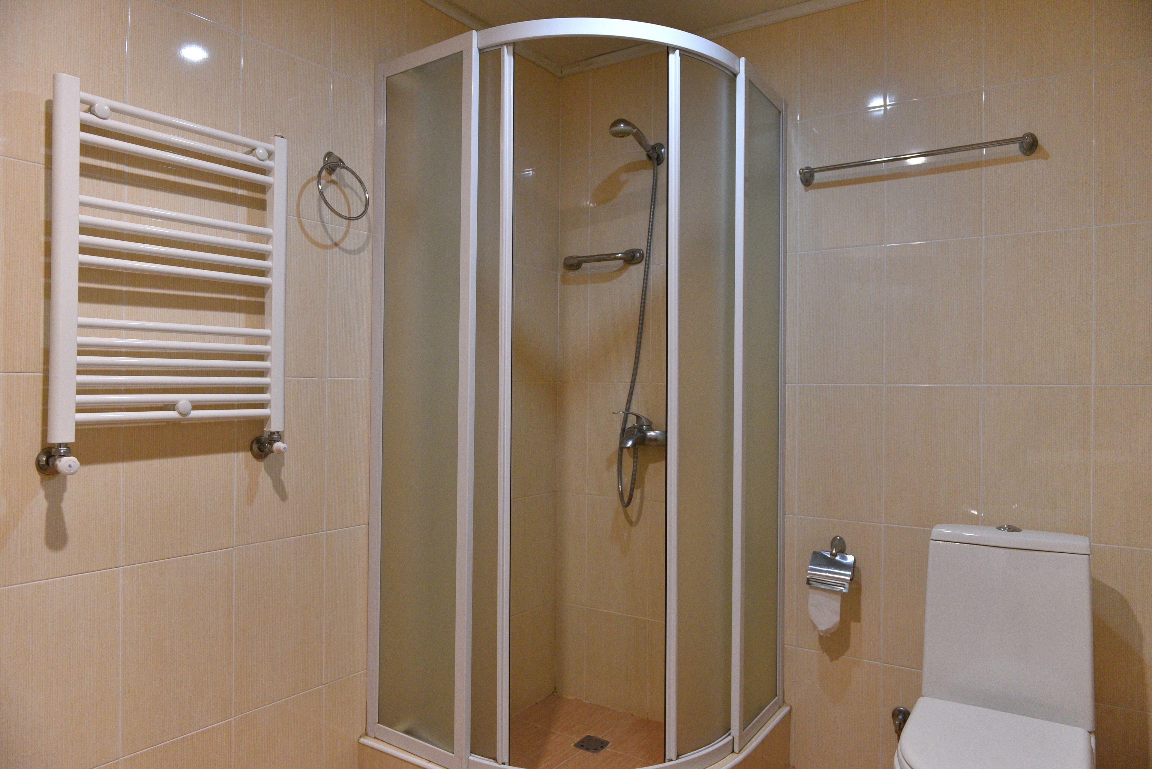 A shower enclosure with a glass door, a towel rack, and a toilet.