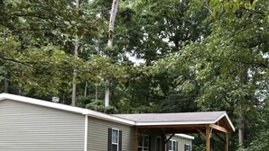 Une maison à deux étages dotée d’une terrasse couverte et d’un barbecue.