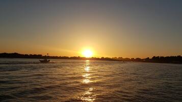 Un atardecer sobre un río tranquilo con barcos.