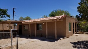 A single-story building with a tiled roof, a fenced area, and a clear sky.