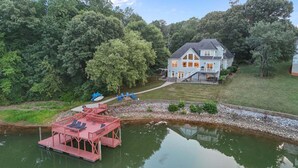 A house with a dock and chairs by a lake, surrounded by trees. - Big Splash-Lakefront Retreat with Hot Tub & Dock (Sherrills Ford)