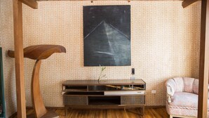 Een kamer met een houten entertainmentkast, een schoolbord en behang met een patroon.
