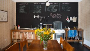 Een keuken met een schoolbord waarop een menukaart staat met gerechten zoals 'Seco de pollo' en 'Ceviche de camarones'.