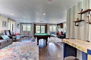 Relax in a spacious indoor recreational area with a pool table, billiards table, and comfortable seating areas.