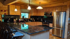 A modern kitchen with wooden cabinets, a large island, stainless steel appliances, and bar stools. - Don't Miss This View!!! Secluded Mountaintop Cabin- w/ Hot tub & Shuffleboard (Waynesville)