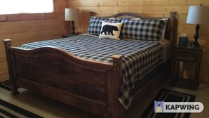 A wooden bed with a checkered bedspread and pillows, two bedside tables with lamps, and a wooden floor. - Don't Miss This View!!! Secluded Mountaintop Cabin- w/ Hot tub & Shuffleboard (Waynesville)