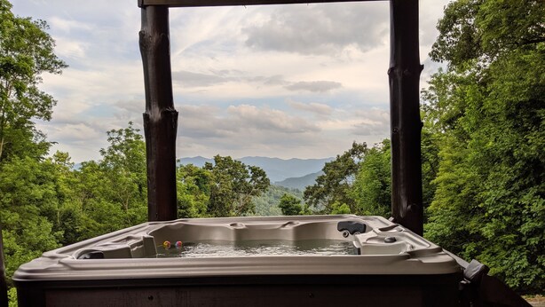 A hot tub with a view of mountains and trees. - Don't Miss This View!!! Secluded Mountaintop Cabin- w/ Hot tub & Shuffleboard (Waynesville)