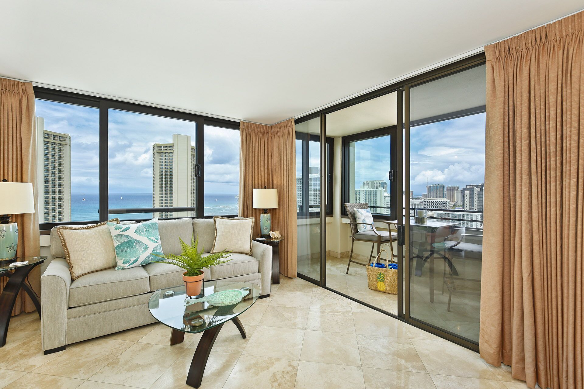 Uma sala de estar moderna com sofá, mesa de centro e vista para a cidade e oceano através de grandes janelas.