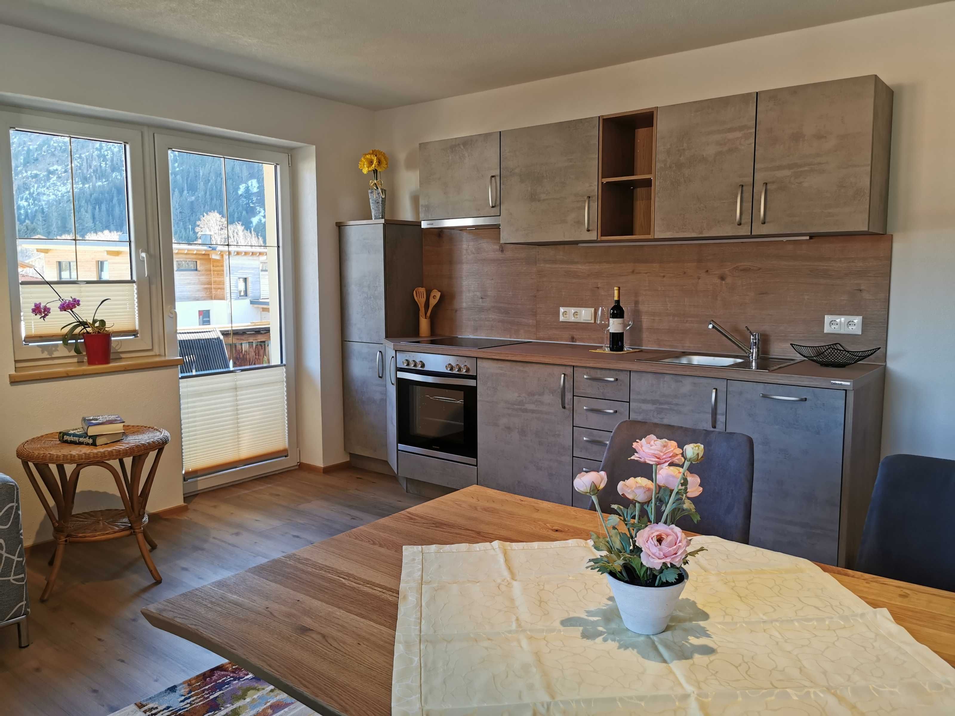 Une cuisine moderne avec des meubles en bois, un four encastré et une fenêtre donnant sur une forêt.