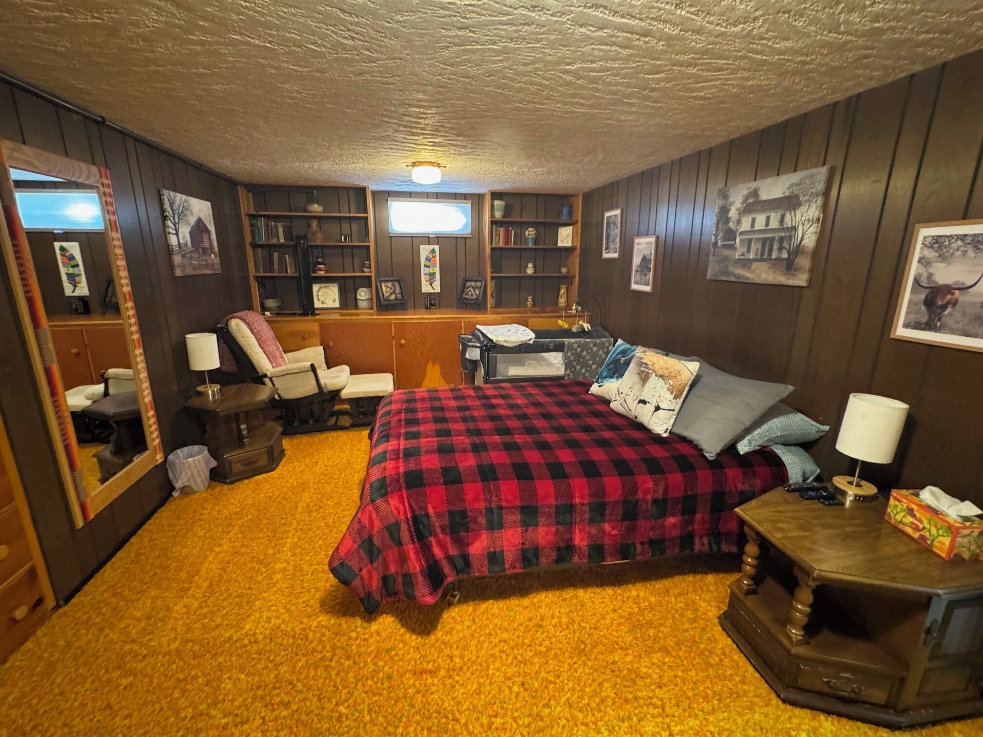 A cozy bedroom with a bed, a chair, a desk, and a bookshelf.