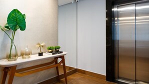 A reception desk with a large green plant, two glass vases, and a decorative fan.