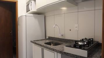 A compact kitchen with white cabinets, a granite countertop, a built-in gas stove, and a stainless steel sink.
