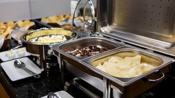 A buffet setup with various food items in stainless steel containers.